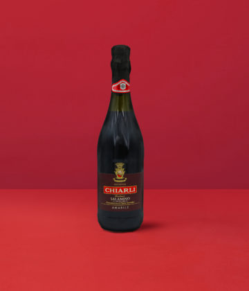 Bouteille de Lambrusco Classico Salamino - Chiarli DOC sur un fond rouge élégant.