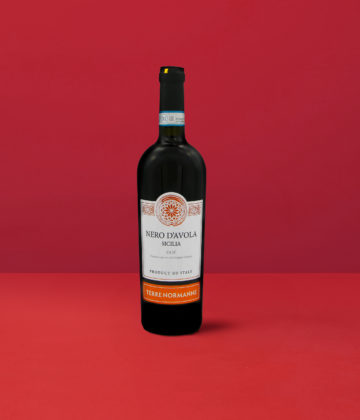 Flasche Nero d&#039;Avola - Terre Normanne DOP, die das intensive Rot und die granatroten Reflexe widerspiegelt, die für den sizilianischen Wein charakteristisch sind.