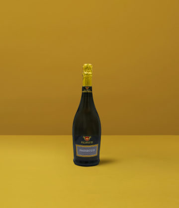 Filipetti Extra Dry Prosecco-Flasche auf gelbem Hintergrund, ein Symbol für Finesse und italienische Feierlichkeit.